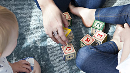 Two children playing blocks with an adult