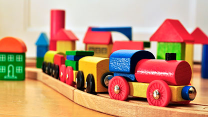 Wooden train on rail passing through city made of blocks