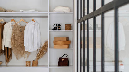 A minimalist retail store display with clothing, shoes, and accessories arranged on white shelves