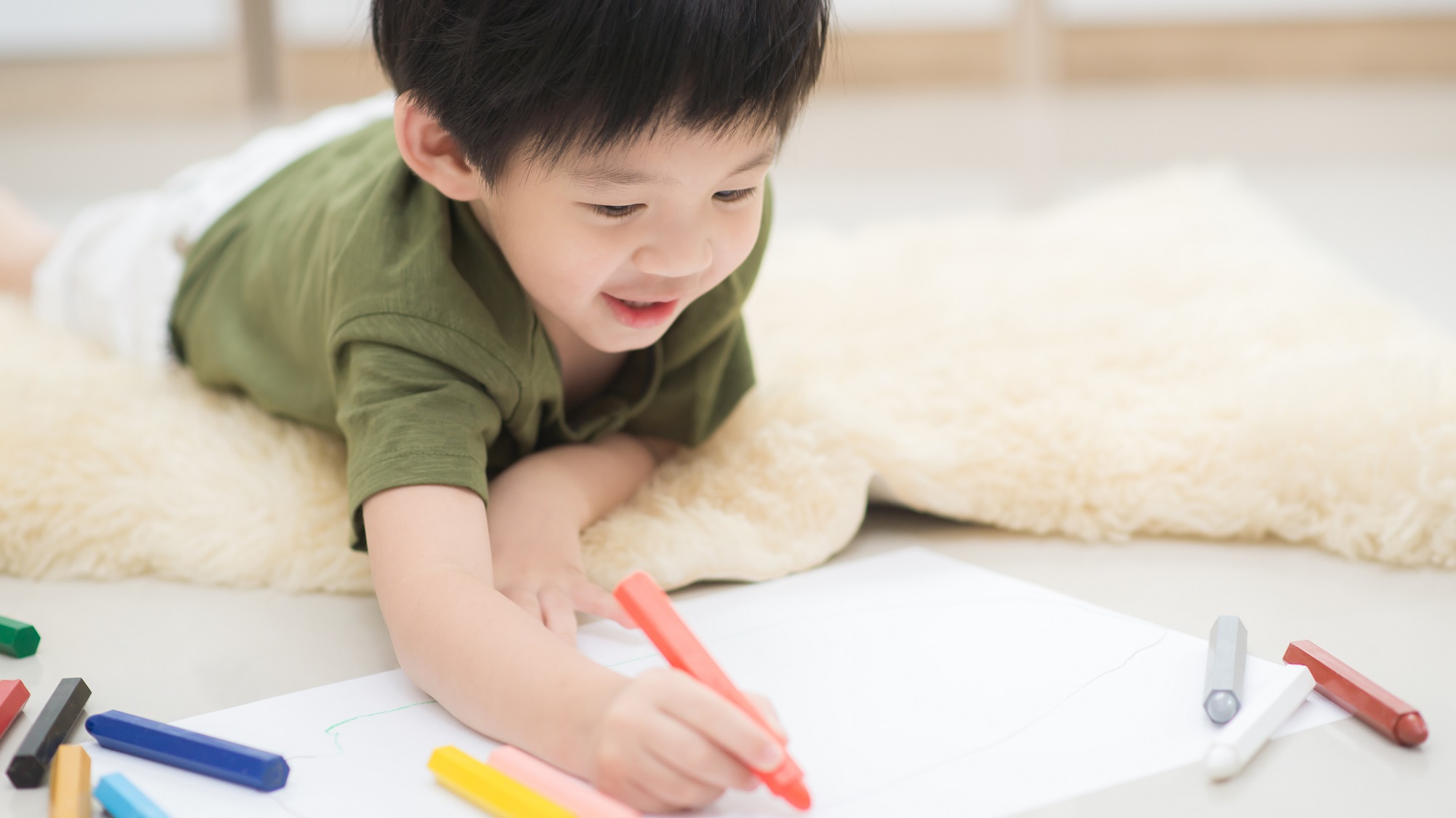 A Japanese boy drawing on a paper.