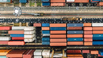 Bird's-eye view of a shipping container yard with rows of colorful containers and vehicles