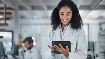 woman holding a tablet, smiling in laboratory reviewing data