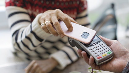 A person making a contactless payment with a smartphone at a card reader