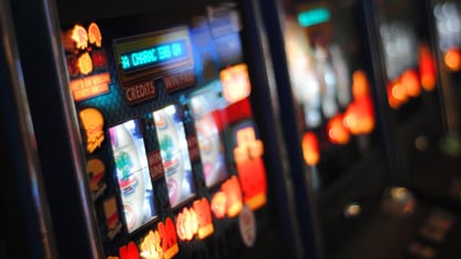 Close-up of a brightly lit slot machine displaying reels and credits in a casino setting.