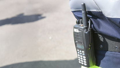 A close-up view of a walkie talkie strapped to someone's belt