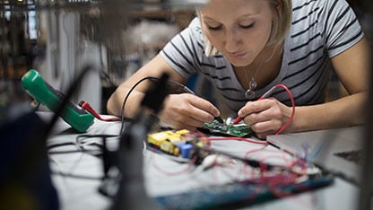 Woman using tools working on an electrical chip