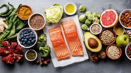 A variety of healthy foods including salmon, vegetables, fruits, nuts, seeds, and grains