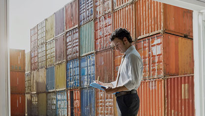 Man with checklist in front of cargo containers