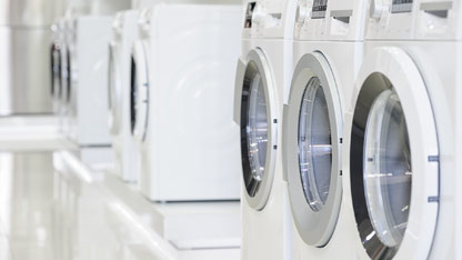 Row of modern washing machines displayed in a bright showroom