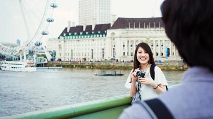 Woman holding camera near riverside tourist area