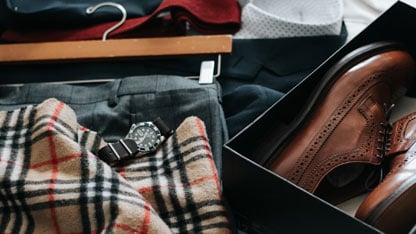 A collection of men's clothing and accessories, including a watch, plaid scarf, and dress shoes