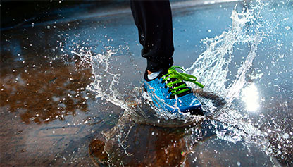 Athletic shoe making a splash in a puddle of water